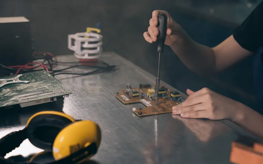 Engineer performing chip-level repair on a circuit board.